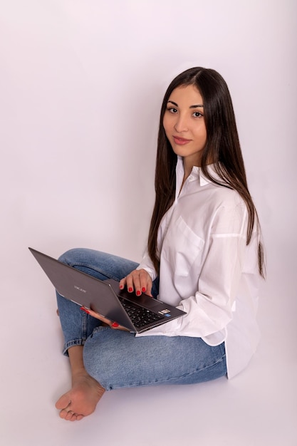 Mulher jovem usando laptop nas mãos em fundo branco trabalho remoto on-line