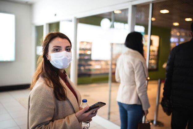 Foto mulher jovem usando máscara de pé no shopping