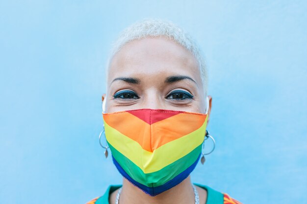 Mulher jovem usando máscara do orgulho gay - conceito de direitos, diversidade, tolerância e identidade de gênero LGBT