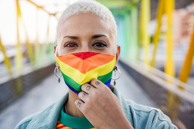 Mulher jovem usando máscara do orgulho gay - conceito de direitos, diversidade, tolerância e identidade de gênero LGBT