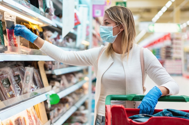 Mulher jovem usando máscara protetora em supermercado durante surto de coronavírus