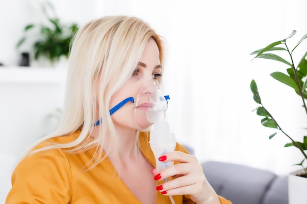 Mulher jovem usando nebulizador para asma e doenças respiratórias em casa