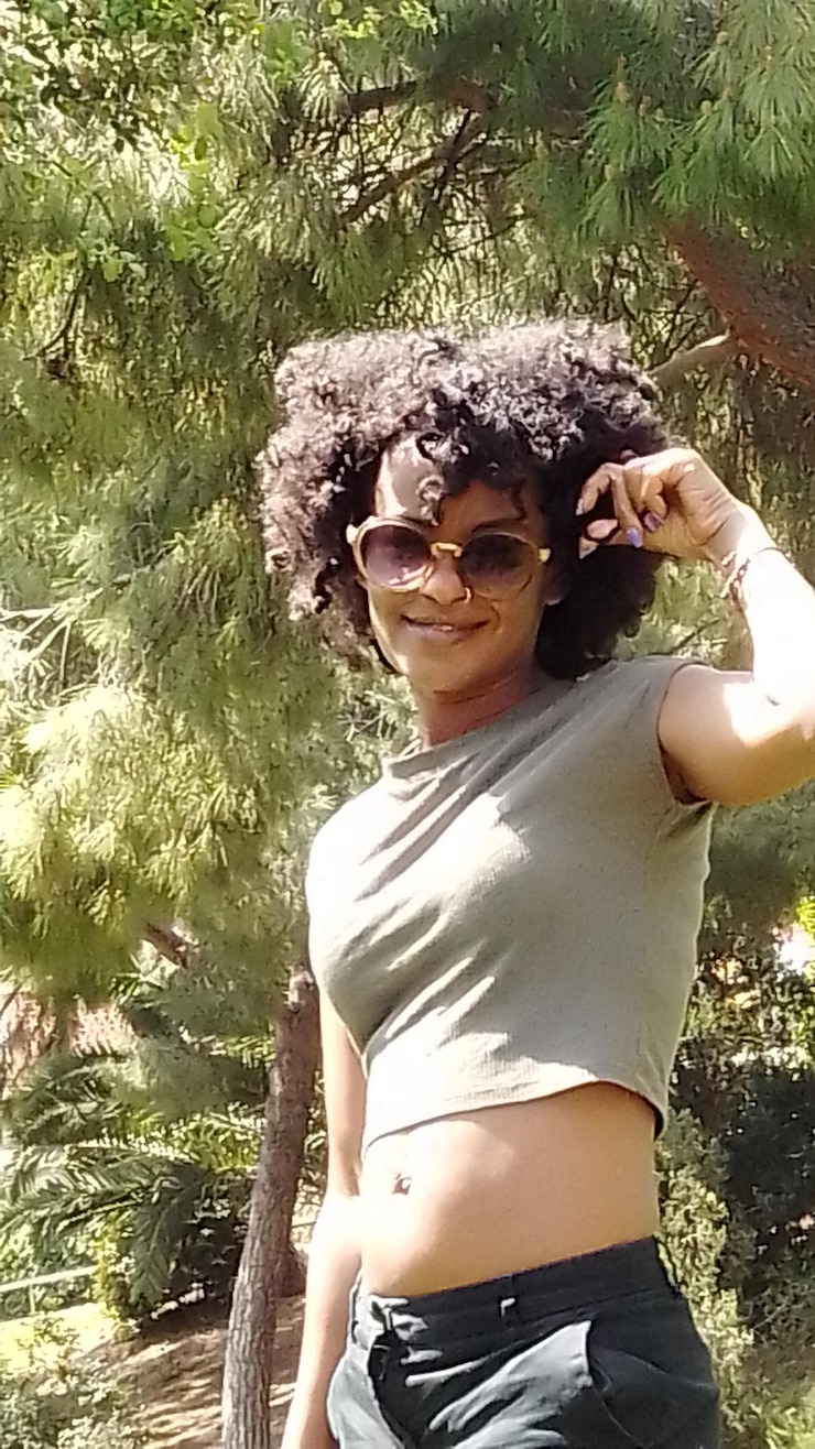 Foto mulher jovem usando óculos de sol de pé contra plantas