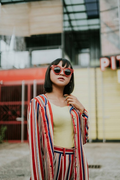 Mulher jovem usando óculos de sol de pé contra um edifício na cidade