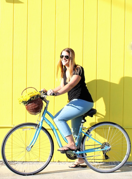 Foto mulher jovem usando óculos de sol enquanto está sentada em uma bicicleta