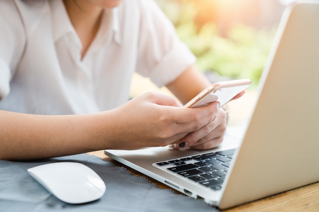 Mulher jovem, usando, smartphone, e, computador laptop, trabalhando, e, negócio, contato, casa