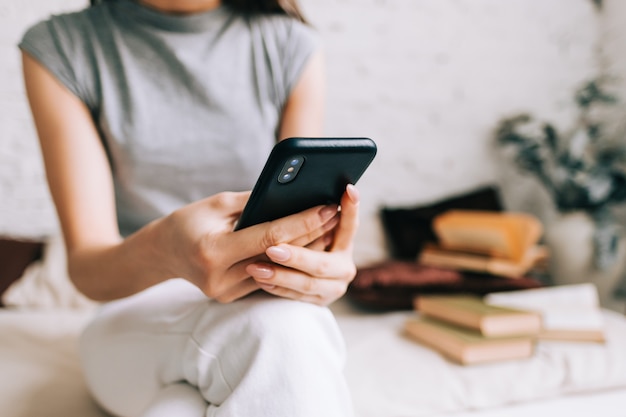 Mulher jovem usando smartphone enquanto descansa em um sofá em casa