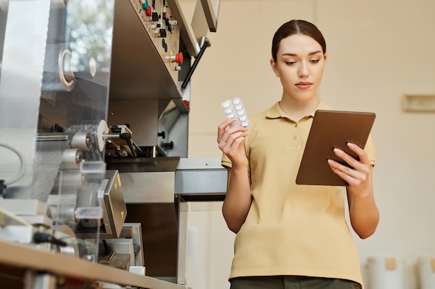 Mulher jovem usando tablet digital em fábrica farmacêutica