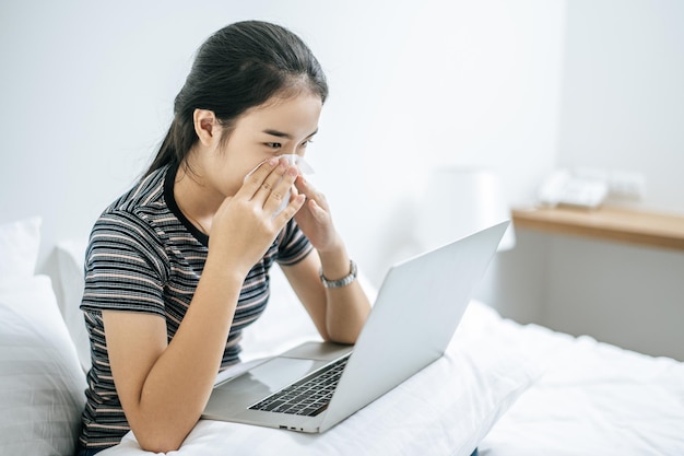 Mulher jovem usando telefone móvel enquanto está sentada na cama em casa