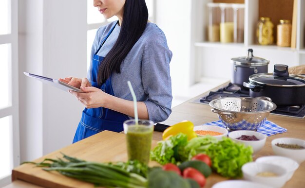 Mulher jovem, usando, um, tabuleta, computador, cozinhar, em, dela, cozinha