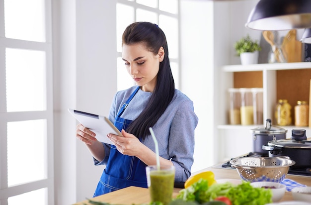 Mulher jovem, usando, um, tabuleta, computador, cozinhar, em, dela, cozinha