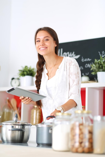 Mulher jovem, usando, um, tabuleta, computador, cozinhar, em, dela, cozinha