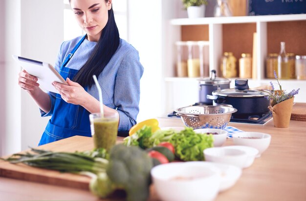 Foto mulher jovem, usando, um, tabuleta, computador, cozinhar, em, dela, cozinha