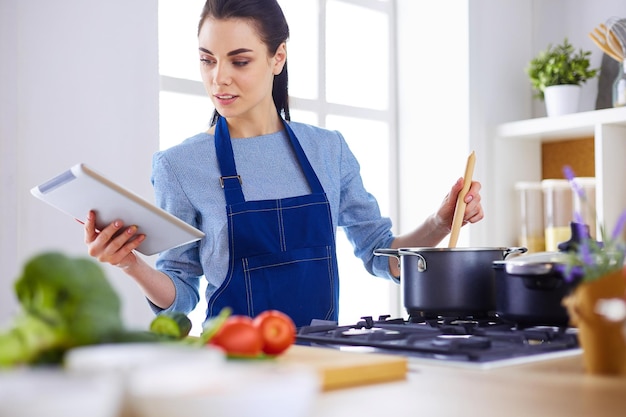 Mulher jovem, usando, um, tabuleta, computador, cozinhar, em, dela, cozinha