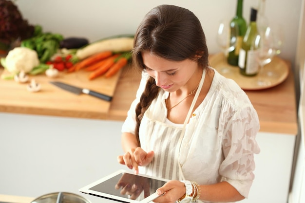 Foto mulher jovem, usando, um, tabuleta, computador, cozinhar, em, dela, cozinha