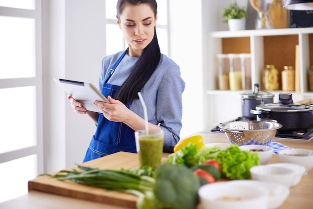 Mulher jovem, usando, um, tabuleta, computador, cozinhar, em, dela, cozinha