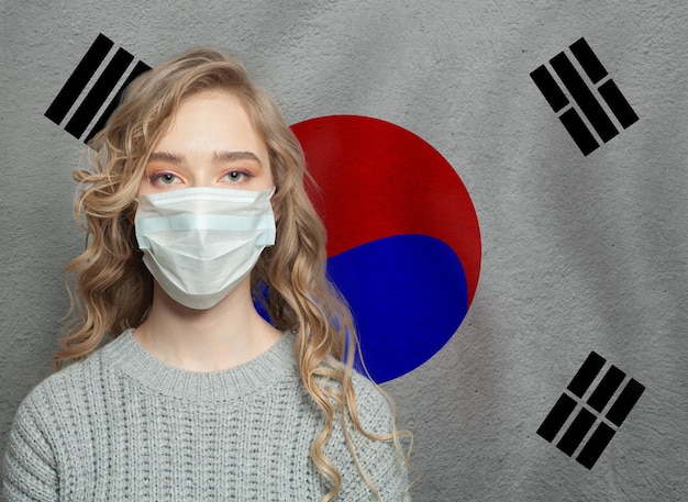 Foto mulher jovem usando uma máscara facial com a bandeira da coreia conceito de epidemia de gripe e proteção contra vírus
