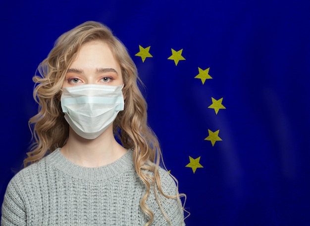 Foto mulher jovem usando uma máscara facial com a bandeira da ue conceito de epidemia de gripe e proteção contra o vírus