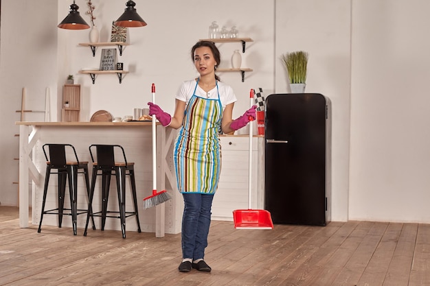 Mulher jovem varrendo o chão da cozinha