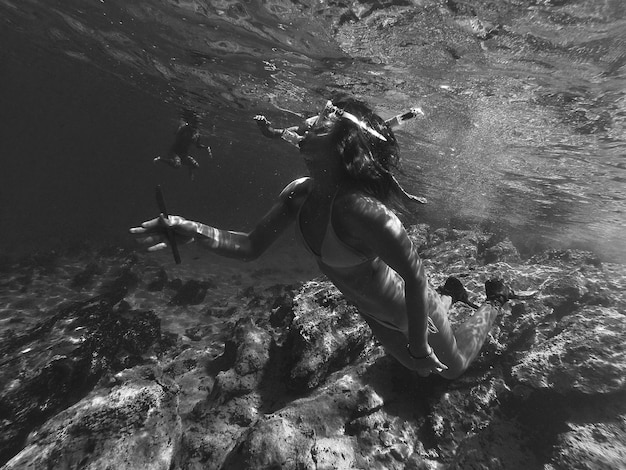 Foto mulher jovem vestindo biquíni nadando debaixo d'água no oceano