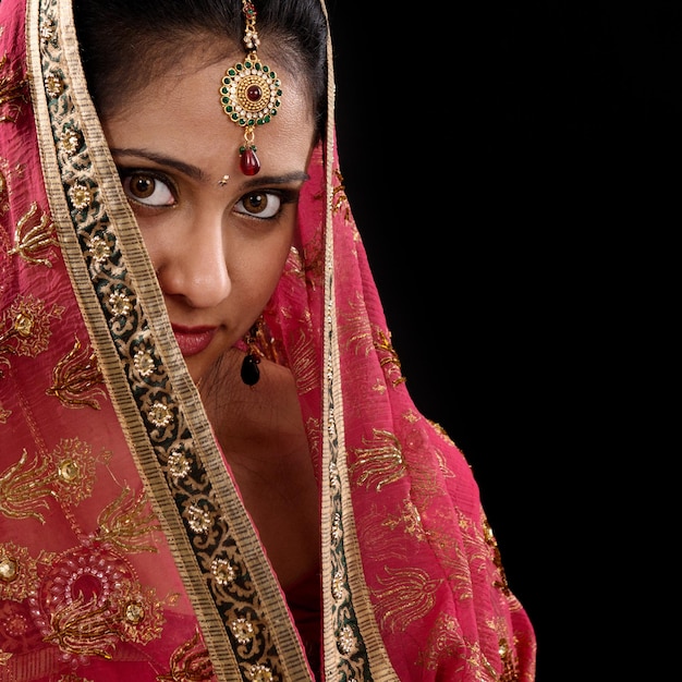 Foto mulher jovem vestindo sari vermelho de pé contra fundo preto