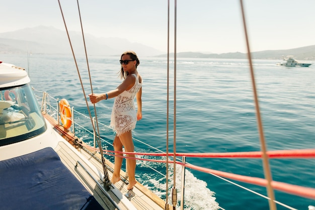 Mulher jovem vestindo trajes de banho de pé em um barco no mar contra o céu