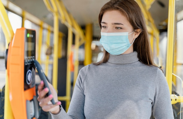 Mulher jovem viajando de ônibus municipal, pagando com cartão de ônibus