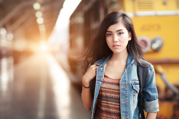 Mulher jovem viajante com mochila esperando trem