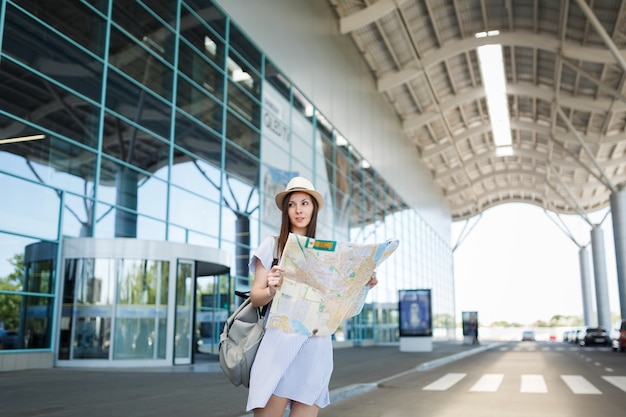 Mulher jovem viajante turista com mochila em pé no aeroporto internacional, segurando um mapa de papel