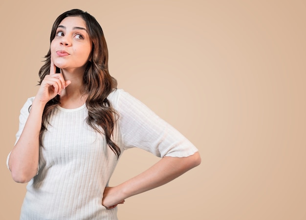 Mulher latina bonita jovem olhando de soslaio com expressão duvidosa e cética.