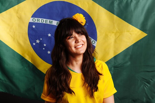 Mulher latina com bandeira do Brasil rindo e sorrindo em apoio ao fã de futebol brasileiro