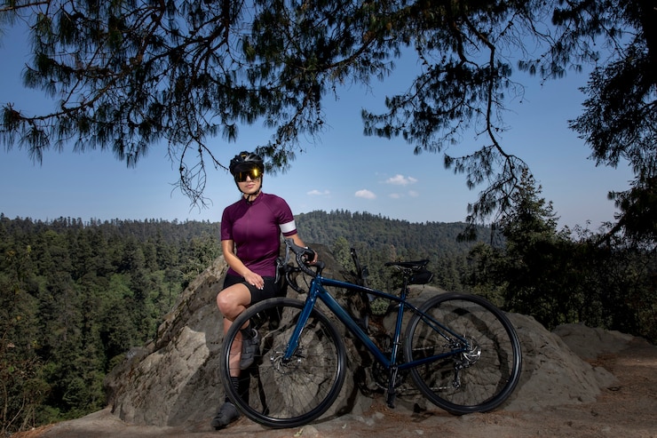 Foto mulher latina com bicicleta descansando na floresta com uma paisagem de árvores ao fundo