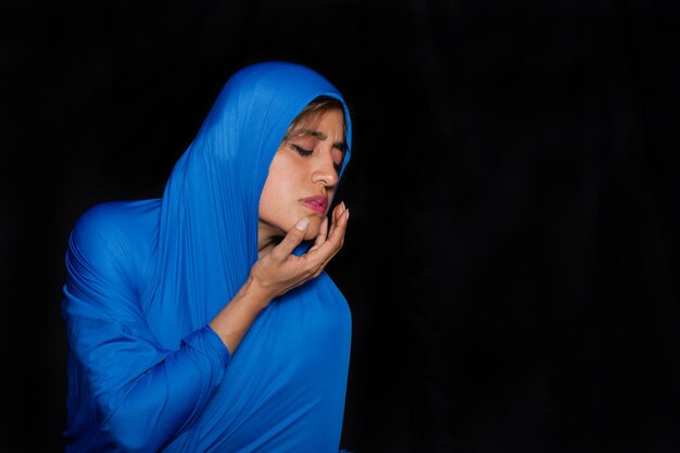 Mulher latina com características indígenas com corpo e cabeça envoltos em um pano azul