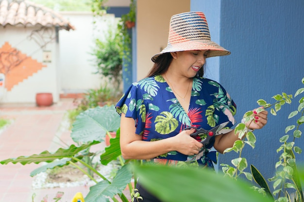 Mulher latina cuidando das plantas em seu jardim. floresta urbana.