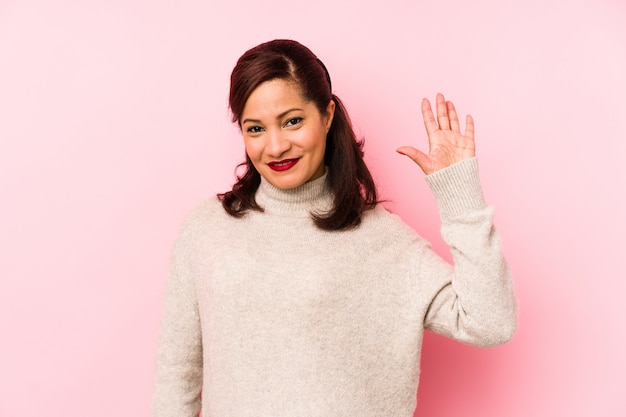 Mulher Latina da Idade Média em uma parede rosa sorrindo alegre mostrando o número cinco com os dedos.