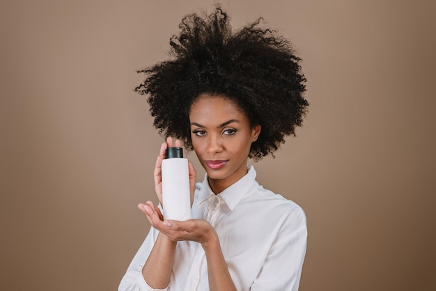 Mulher latina de beleza com penteado afro Mulher brasileira segurando embalagem de xampu em branco