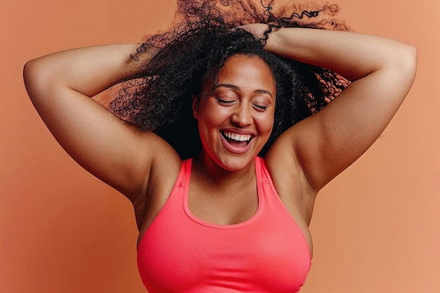 Mulher latina de cabelos encaracolados com uma camisola vermelha rindo com as mãos atrás da cabeça encarnando alegria e confiança em sua jornada de fitness