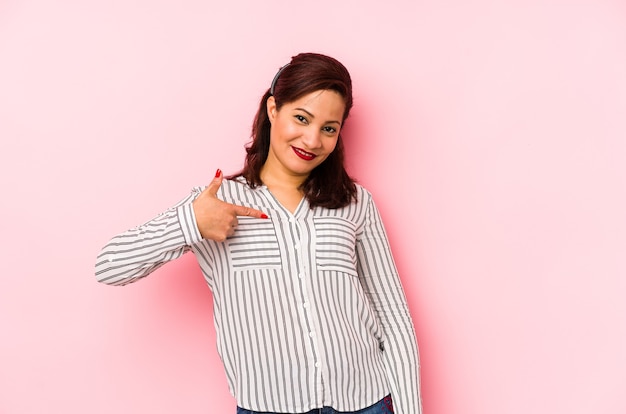 Mulher latina de meia-idade isolada em uma pessoa de fundo rosa apontando com a mão para um espaço de cópia de camisa, orgulhosa e confiante