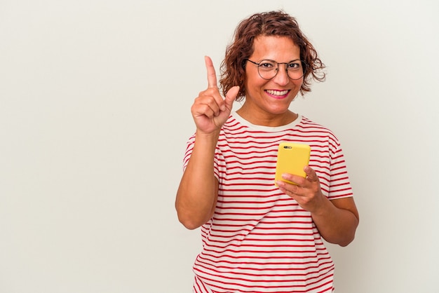 Mulher latina de meia-idade isolada no fundo branco, mostrando o número um com o dedo.