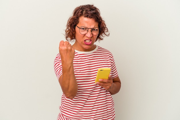 Foto mulher latina de meia-idade isolada no fundo branco, mostrando o punho para a câmera, expressão facial agressiva.