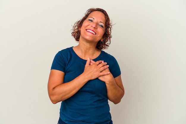 Mulher latina de meia-idade isolada no fundo branco rindo mantendo as mãos no coração, o conceito de felicidade.