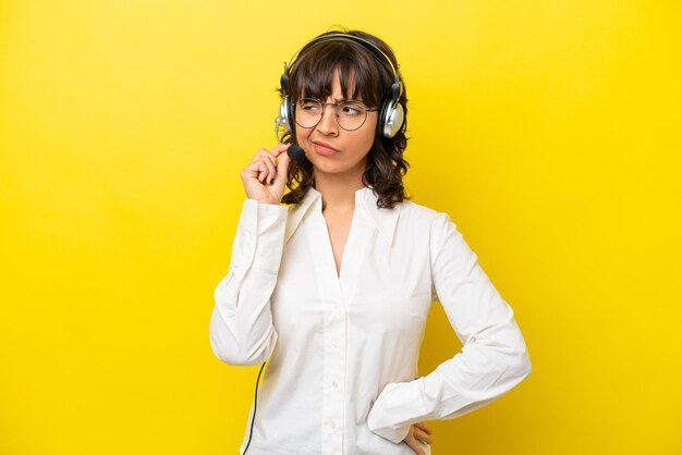 Mulher latina de telemarketing trabalhando com um fone de ouvido isolado em fundo amarelo