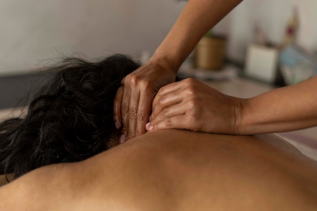 Mulher latina deitada de costas recebendo tratamento de massagem ayurveda