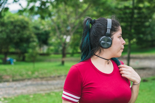 mulher latina em um parque ouvindo música, olhando curiosa e distraidamente para a direita