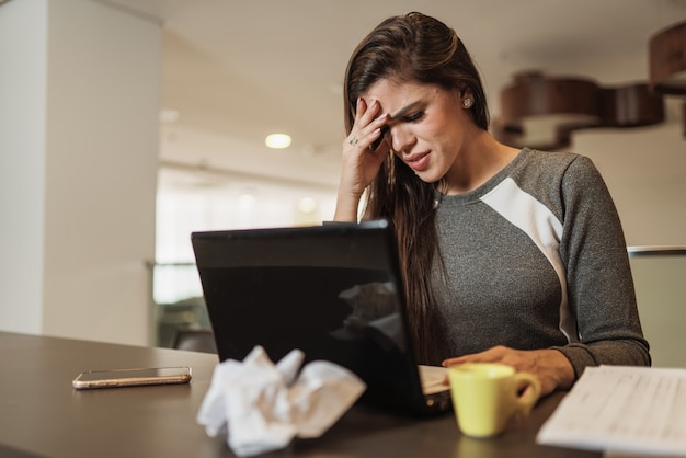 Mulher latina estressada com enxaqueca com um laptop