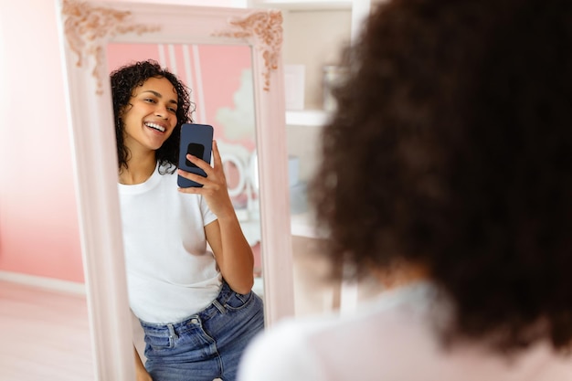 Foto mulher latina feliz a tirar uma selfie no espelho.