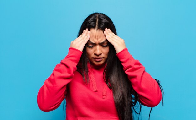 Mulher latina parecendo estressada e frustrada, trabalhando sob pressão, com dor de cabeça e preocupada com problemas