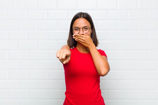 Mulher latina rindo de você, apontando para a câmera e tirando sarro ou zombando de você