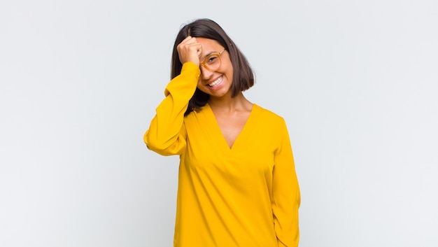 Mulher latina rindo e batendo na testa como se dissesse oh! Eu esqueci ou isso foi um erro estúpido