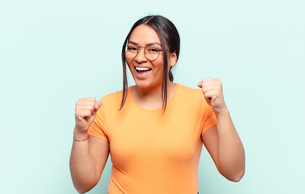 Mulher latina se sentindo chocada, animada e feliz, rindo e comemorando o sucesso, dizendo uau!